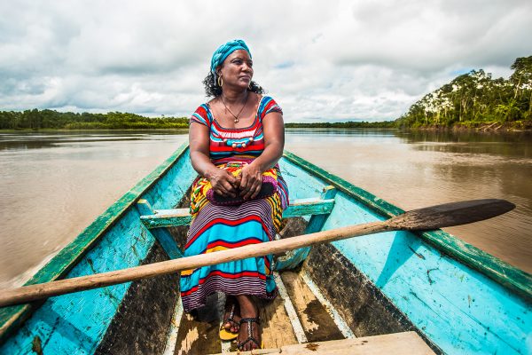 A community member in traditional dress sits in a boat in the Pacific Forest Communities project.